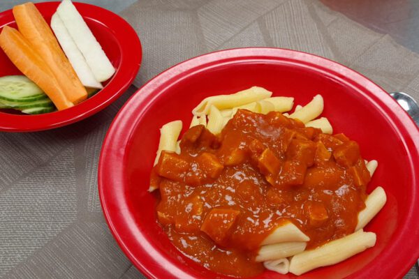 Geflügelwurstgulasch mit Penne und Gemüsesticks